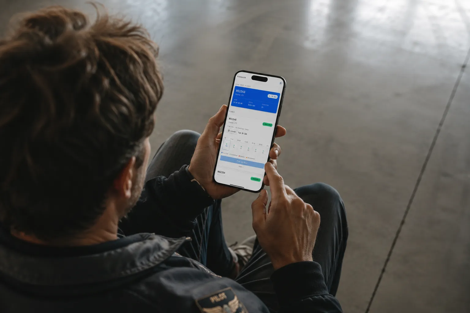 A pilot checking the day's bookings on the Hangarr app from the hangar